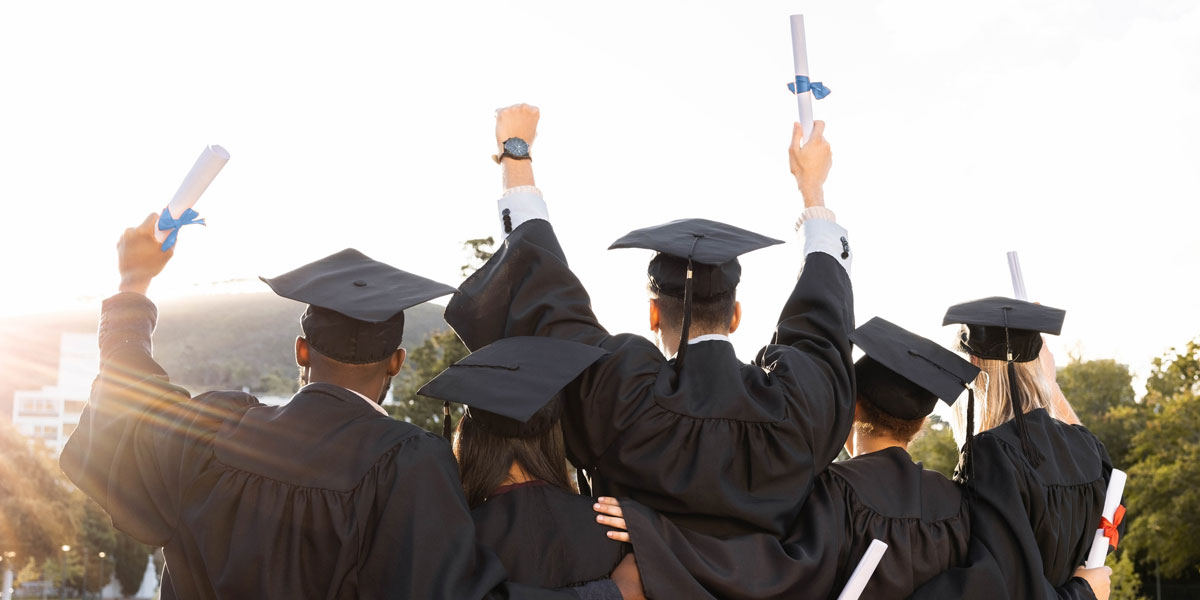 photo of graduates in caps and gowns posing for a picture from behind