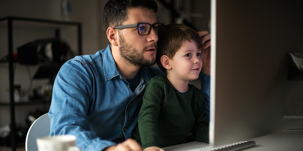 parent sitting with a child in their lap and looking at an assignment for their online degree program