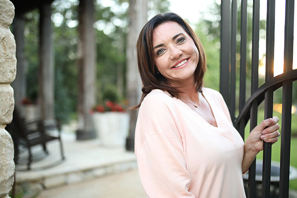 Chantell Cooley smiles as she holds onto an open gate