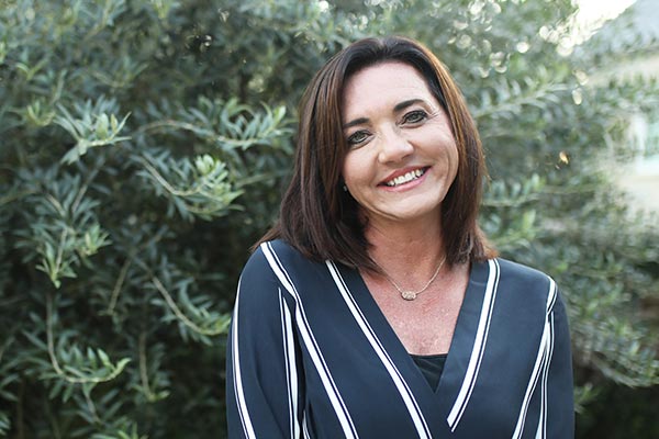 Chantell Cooley smiles in front of greenery